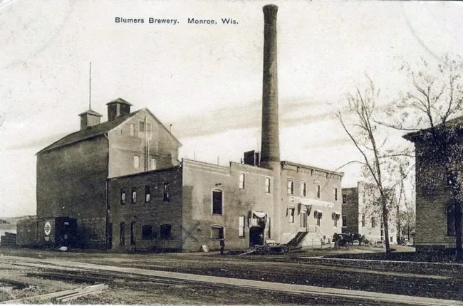 The image shows the historic facade of Minhas Craft Brewery in Monroe, Wisconsin, capturing the essence of its long-standing tradition in brewing excellence. This brewery, known as the oldest in Wisconsin and the second oldest in the United States, continues to thrive with a blend of historical charm and modern innovation. The photo, available at Tavern Trove, illustrates the brewery’s enduring presence and architectural significance ("Minhas Craft Brewery exterior," n.d.).